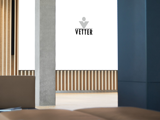 Flurbereich der Vetter Pharma-Fertigung GmbH & Co. KG mit Logo an der Wand.